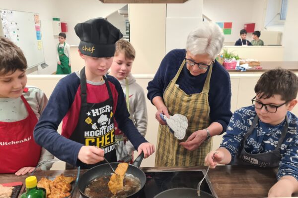 Vier Schüler und eine Lehrerin kochen gemeinsam